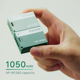 Two Tilta TNP-W126S batteries held between finger and thumb, one Ash Green and one Forest Green, with a 1050mAh NP-W126S capacity callout
