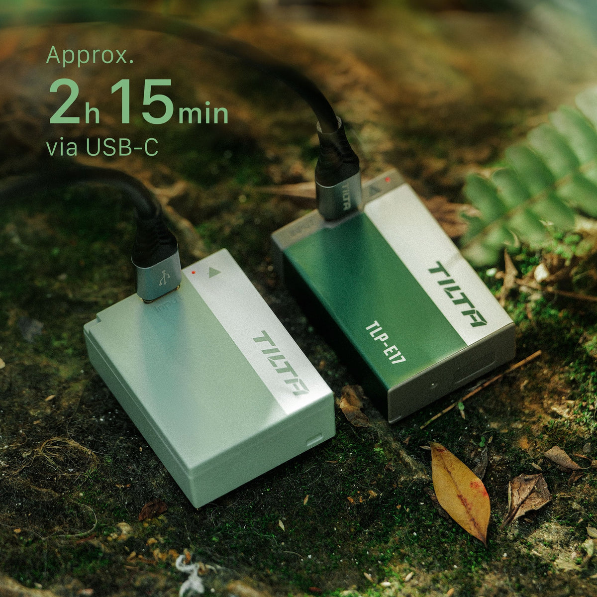 Tilta TLP-E17 batteries in Ash Green and Forest Green charging over USB-C cables on mossy ground, with an approximately 2 hour 15 minute charge time callout